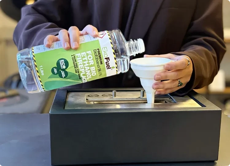 wlewanie paliwa bioetanolowego do palnika za pomocą plastikowego lejka